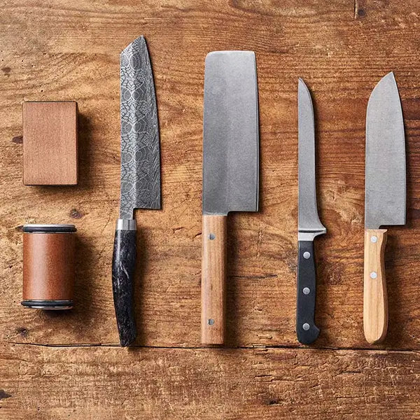 Ensemble de couteaux de cuisine avec manches en bois, lame damassée et accessoires d'affûtage sur planche en bois rustique